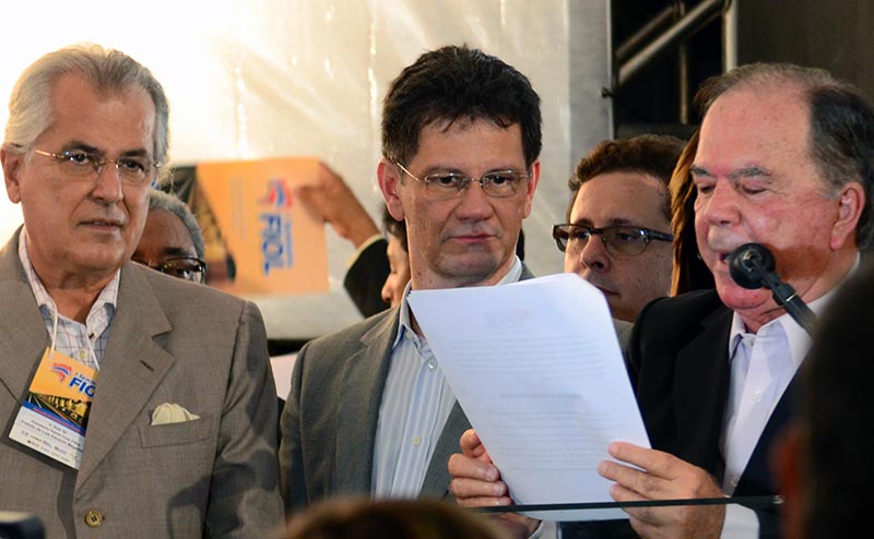 O presidente da Valec, Josias Sampaio Cavalcante Júnior (centro) e o prefeito de Luis Eduardo Magalhães, Humberto Santa Cruz Filho (à esquerda) ouvem o anúncio da carta de reivindicações pelo deputado federal e coordenador do evento, João Leão (à direita).